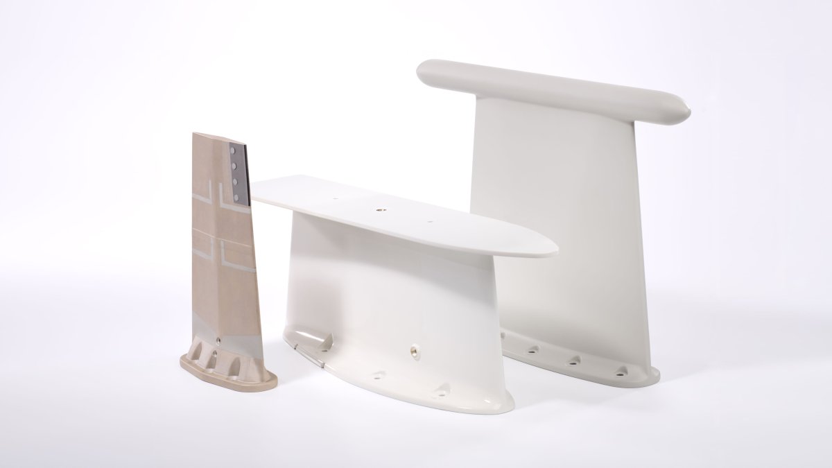 Several light-colored, smoothly shaped components with rounded edges are arranged side by side and vary in size.