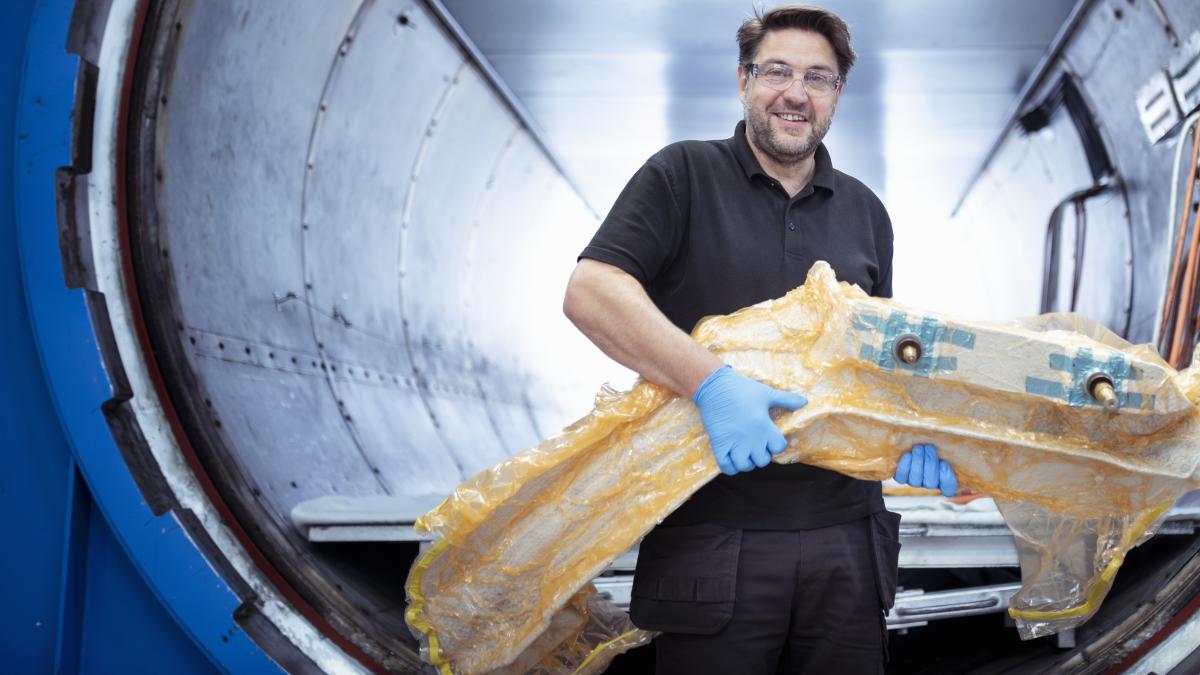 Worker with carbon fibre part in front of autoclave