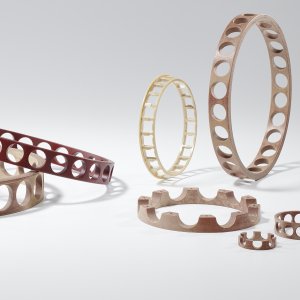 The display features several ball bearing cages in various sizes and colors, some with evenly spaced round recesses and others with textured edges.