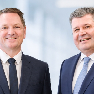 The managing directors of Krempel GmbH are standing against a light-colored background and smiling at the camera.