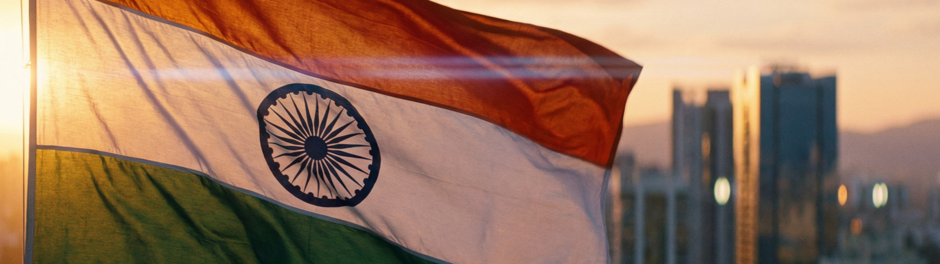 The Indian flag flutters in the sunset, with a skyline visible in the background.