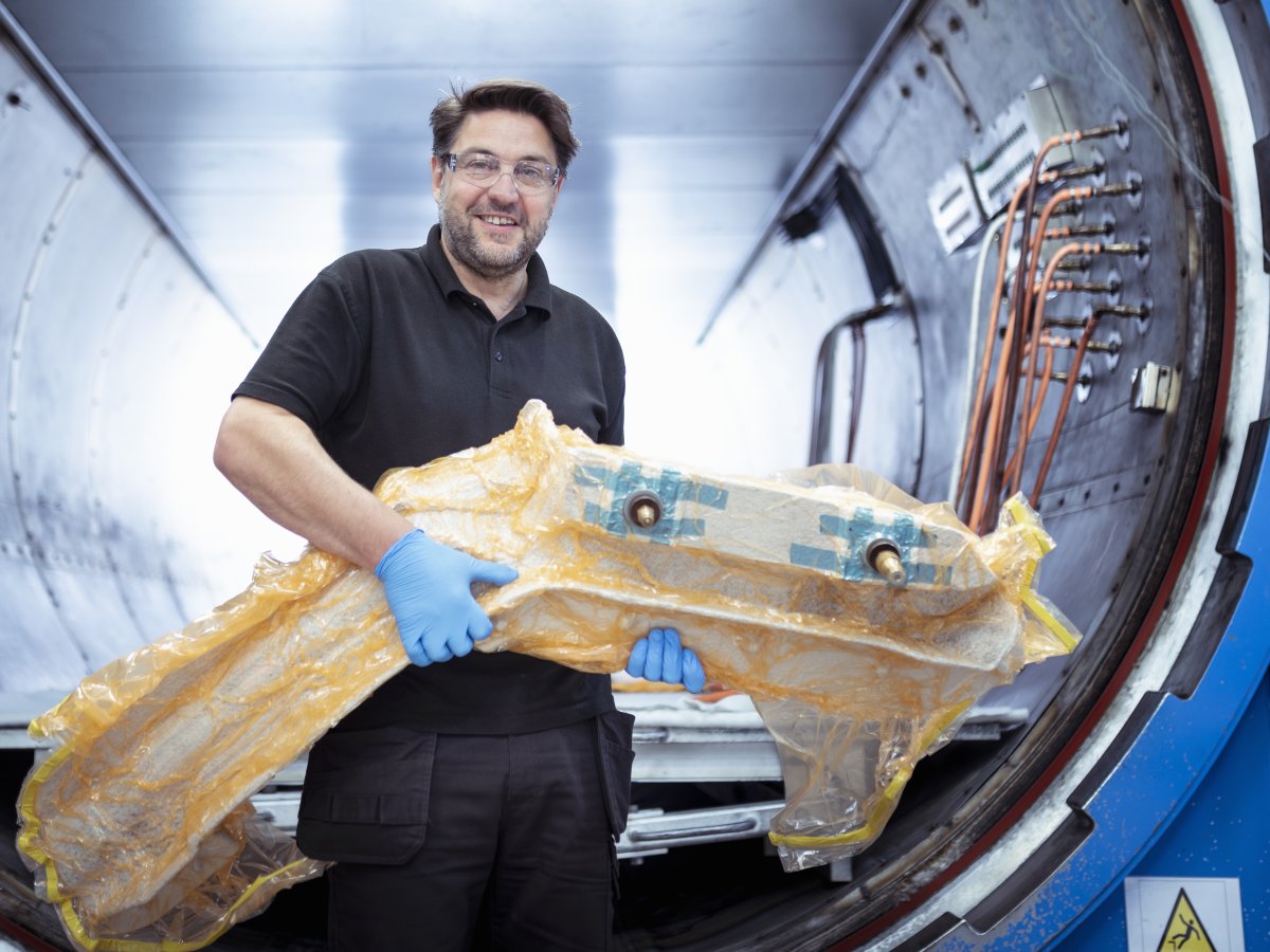 Worker with carbon fibre part in front of autoclave
